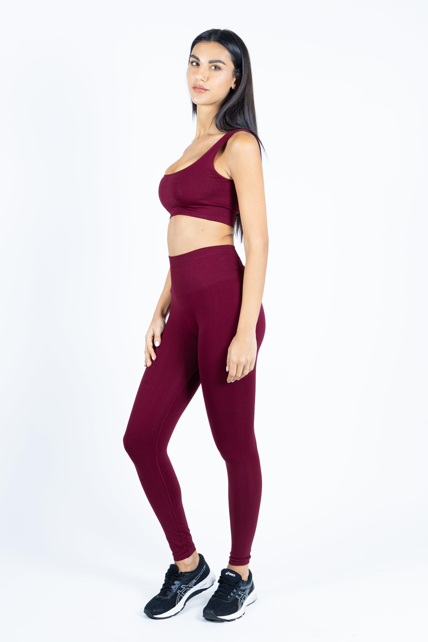 Fitness model wearing a seamless burgundy activewear outfit in an elegant pose.