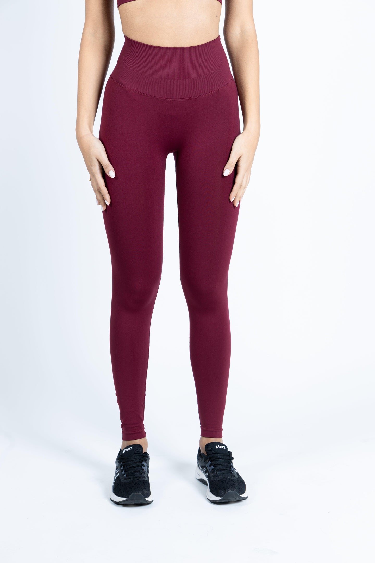 Modella che indossa un completo activewear seamless color borgogna, vista frontale.