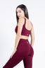 Modella fitness con abbigliamento sportivo seamless color borgogna, posa elegante.