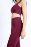 Side view of a woman in a burgundy activewear set, showing flexibility and comfort.
