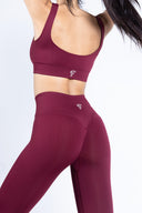 Modella a figura intera con un completo seamless borgogna, ideale per allenamenti e yoga.